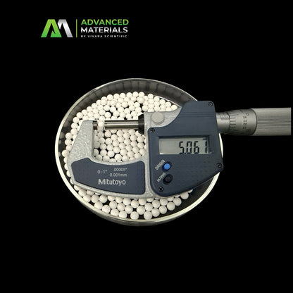 White spherical beads measured inside a metal dish with a Mitutoyo digital micrometer over them, on a black background. Advanced Materials by Vivara Scientific logo is visible in the top left.