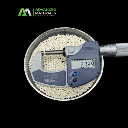 A digital Mitutoyo micrometer shown measuring white spherical pellets in a metal bowl, with the brand logo 'Advanced Materials by Vivana Scientific' in the top-left corner against a solid black background.